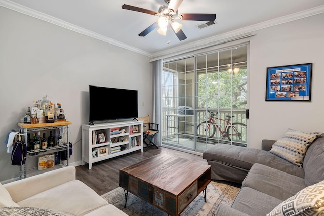 living room featuring visible vents, crown molding, baseboards, wood finished floors, and a ceiling fan