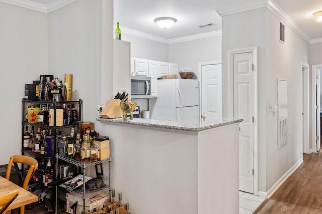 kitchen with visible vents, stainless steel microwave, crown molding, and freestanding refrigerator