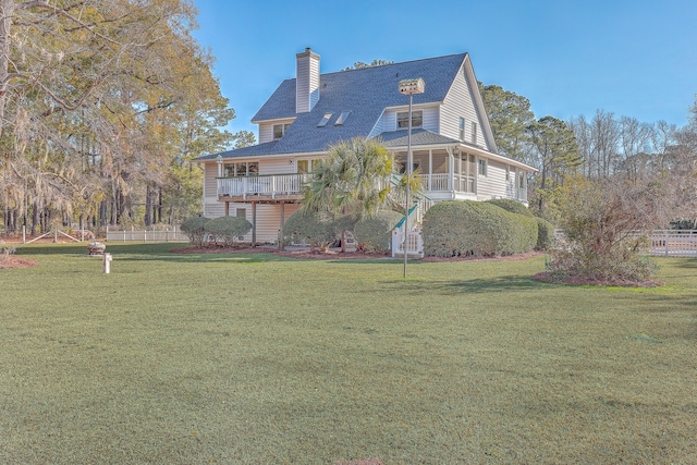 back of property featuring a wooden deck, a yard, and a sunroom