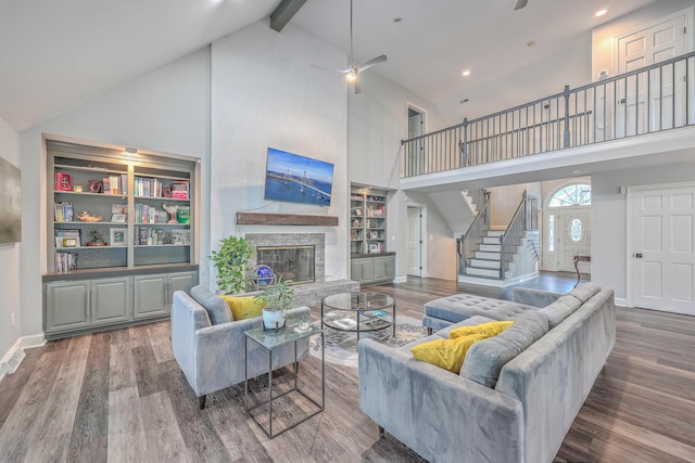 living room featuring a high ceiling, hardwood / wood-style floors, ceiling fan, and beamed ceiling