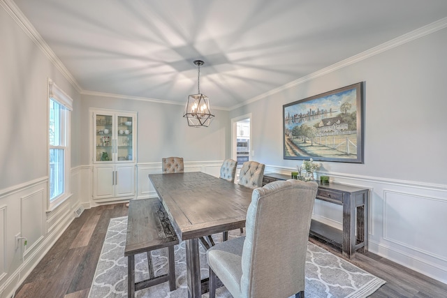 dining area featuring dark wood-type flooring, crown molding, and a chandelier