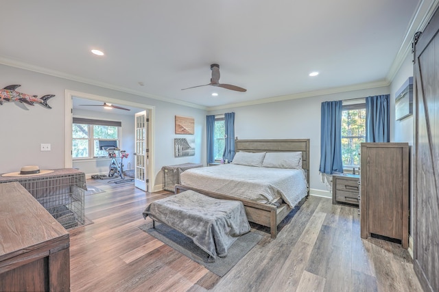 bedroom featuring hardwood / wood-style flooring, ceiling fan, crown molding, and multiple windows