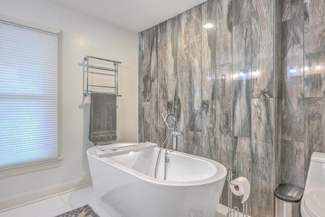 bathroom featuring tile patterned flooring, a tub to relax in, and toilet