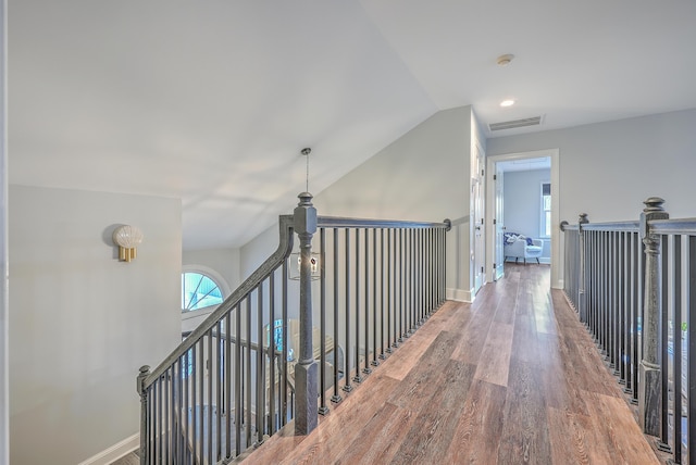 hallway with hardwood / wood-style flooring and vaulted ceiling