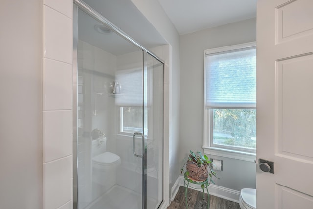 bathroom with wood-type flooring, a shower with door, and toilet