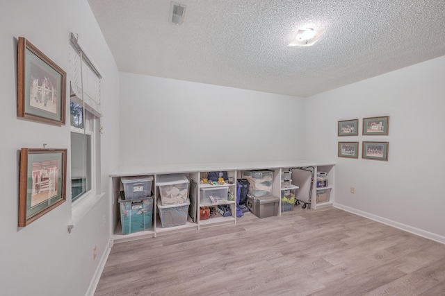 rec room with light hardwood / wood-style floors and a textured ceiling