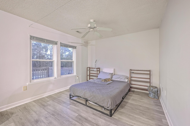 bedroom with light wood-type flooring, a textured ceiling, and ceiling fan