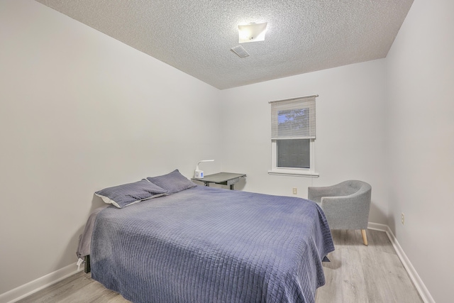 bedroom with light hardwood / wood-style floors and a textured ceiling