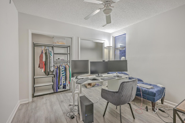 office space featuring ceiling fan, light wood-type flooring, and a textured ceiling