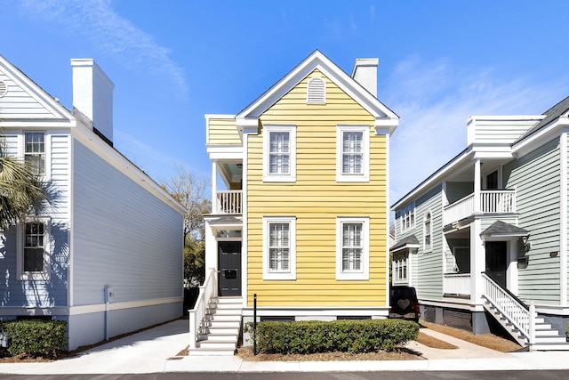 view of front of property featuring entry steps, a chimney, and a balcony