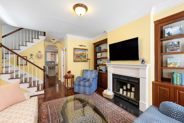 living area with arched walkways, ornamental molding, dark wood-type flooring, stairs, and a fireplace