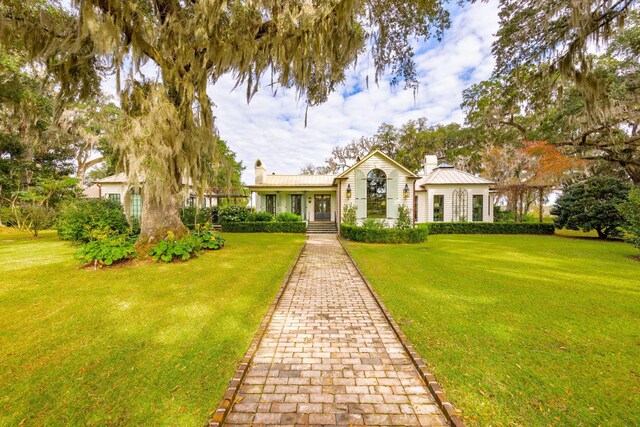 view of front of home with a chimney, a front lawn, a standing seam roof, and metal roof
