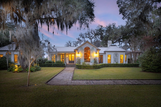 view of front facade with a chimney, a standing seam roof, metal roof, and a front yard