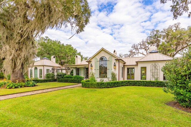 view of front of property with a front lawn, metal roof, a chimney, and a standing seam roof