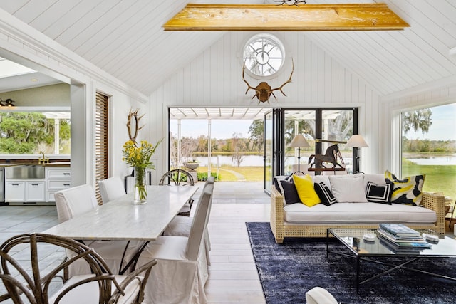 sunroom featuring beamed ceiling, a sink, and a water view
