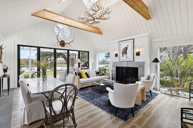 living area with a wealth of natural light, a water view, a chandelier, a tile fireplace, and wood-type flooring