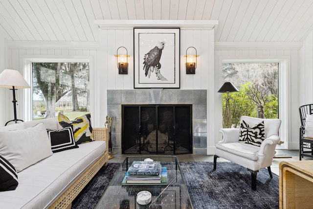 living area with wooden ceiling, wood walls, and a tiled fireplace