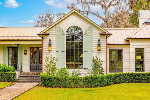 view of front of property featuring a front lawn, a porch, a standing seam roof, and metal roof