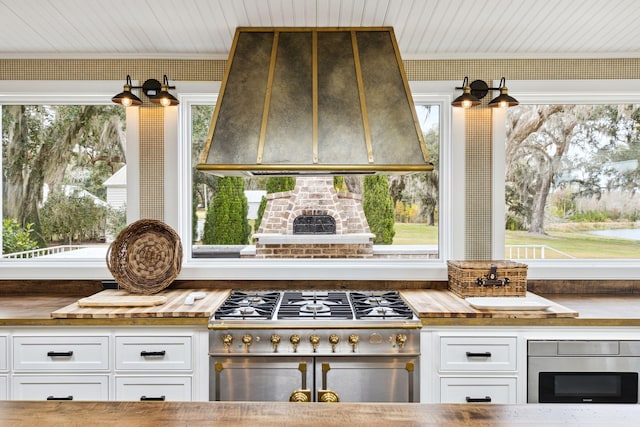 room details with white cabinets, double oven range, extractor fan, wood ceiling, and ornamental molding