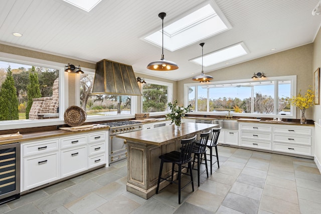 kitchen featuring wine cooler, high end range, butcher block countertops, and a healthy amount of sunlight