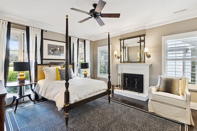 bedroom with ornamental molding, wood finished floors, visible vents, and a fireplace