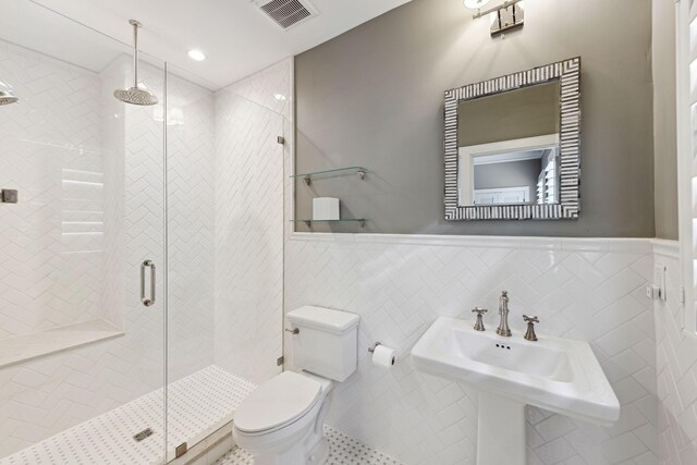 bathroom with a shower stall, toilet, wainscoting, and visible vents