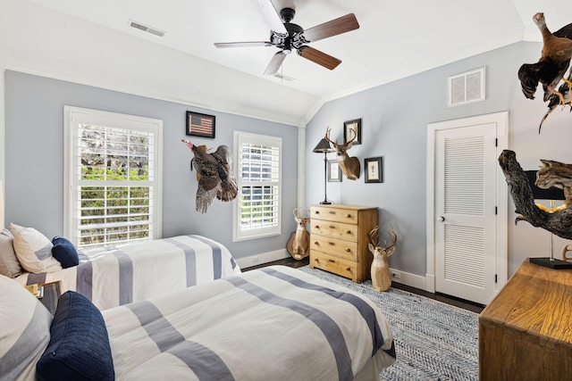 bedroom featuring wood finished floors, visible vents, baseboards, and ornamental molding