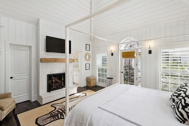 bedroom featuring a fireplace, wood finished floors, wood walls, and access to outside