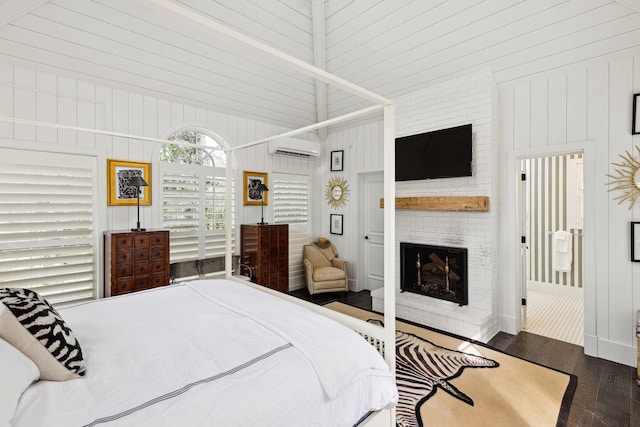 bedroom featuring wooden walls, wood finished floors, a fireplace, and a wall mounted air conditioner