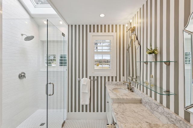 full bathroom with vanity, a skylight, and a stall shower