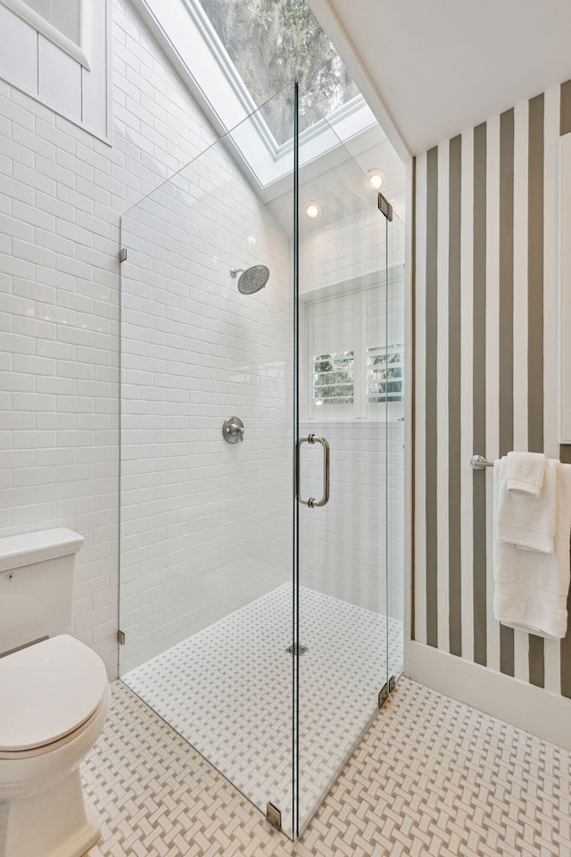 full bath with a skylight, a stall shower, and toilet