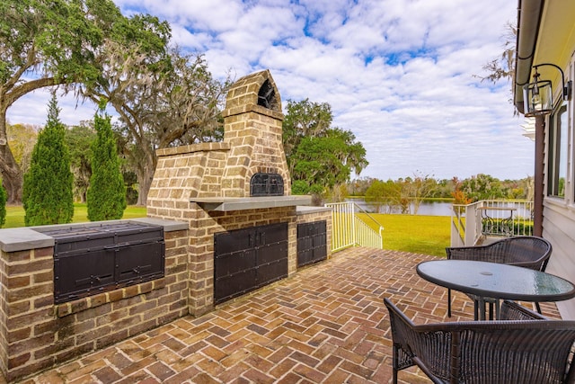 view of patio featuring an outdoor fireplace and a water view