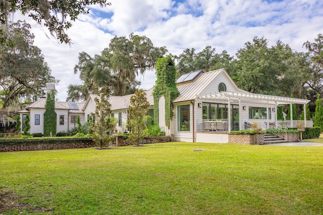 rear view of house with a pergola, a yard, and a standing seam roof