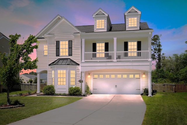 view of front of property featuring fence, a balcony, a front yard, an attached garage, and driveway
