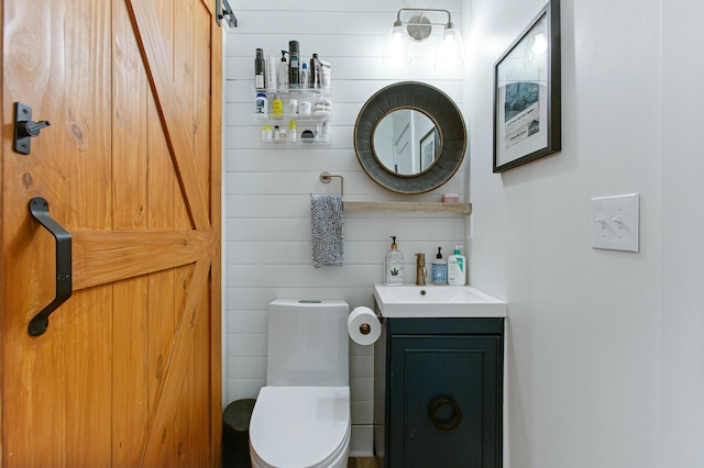 bathroom with vanity, toilet, and wood walls