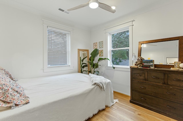 bedroom with multiple windows, light hardwood / wood-style floors, ceiling fan, and crown molding