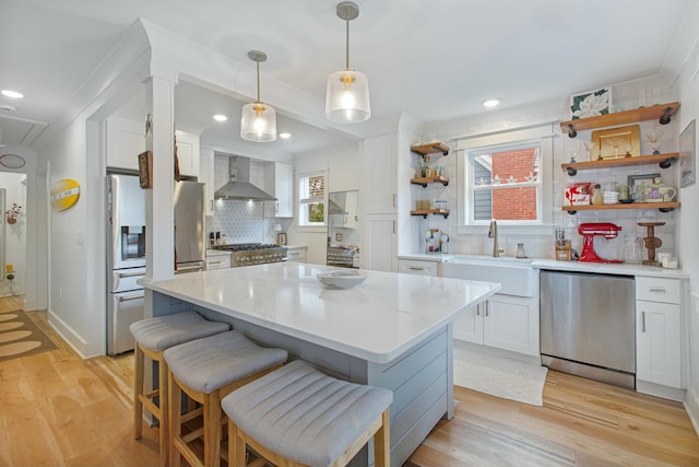 kitchen with white cabinets, stainless steel appliances, and wall chimney range hood