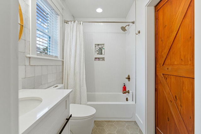 full bathroom with shower / bathtub combination with curtain, tile patterned floors, toilet, vanity, and tile walls