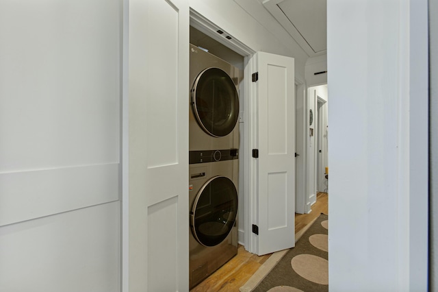 laundry room with light hardwood / wood-style flooring and stacked washer / drying machine