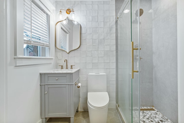 bathroom featuring vanity, a shower with door, tile patterned flooring, toilet, and tile walls