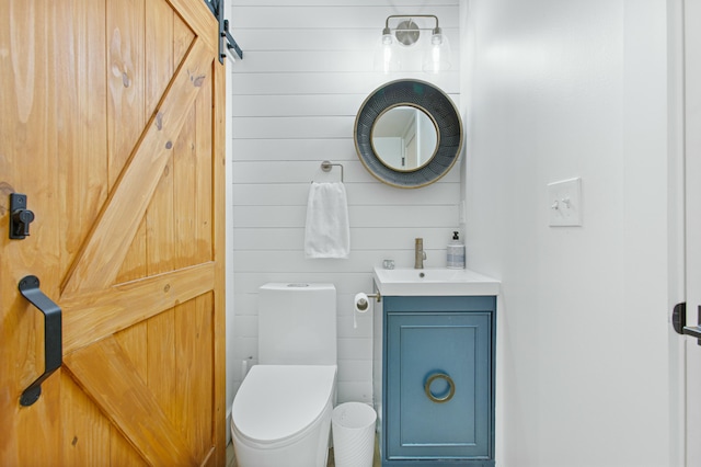 bathroom with wooden walls, vanity, and toilet