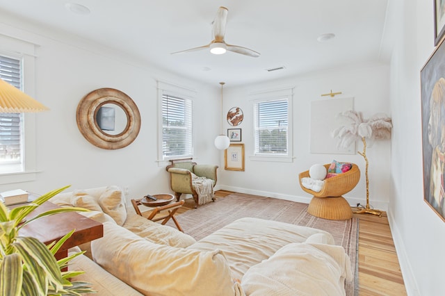 living area featuring ceiling fan, light hardwood / wood-style floors, and ornamental molding