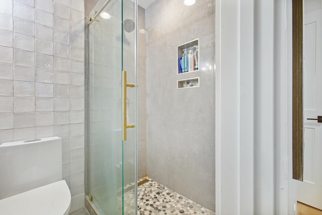 bathroom with a shower with shower door, tile walls, and toilet