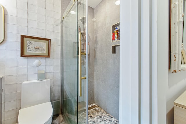 bathroom with toilet, tile walls, and a shower with shower door