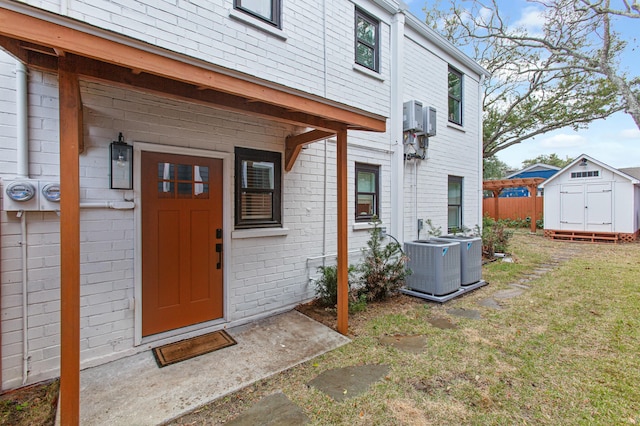 doorway to property with central AC unit and a lawn