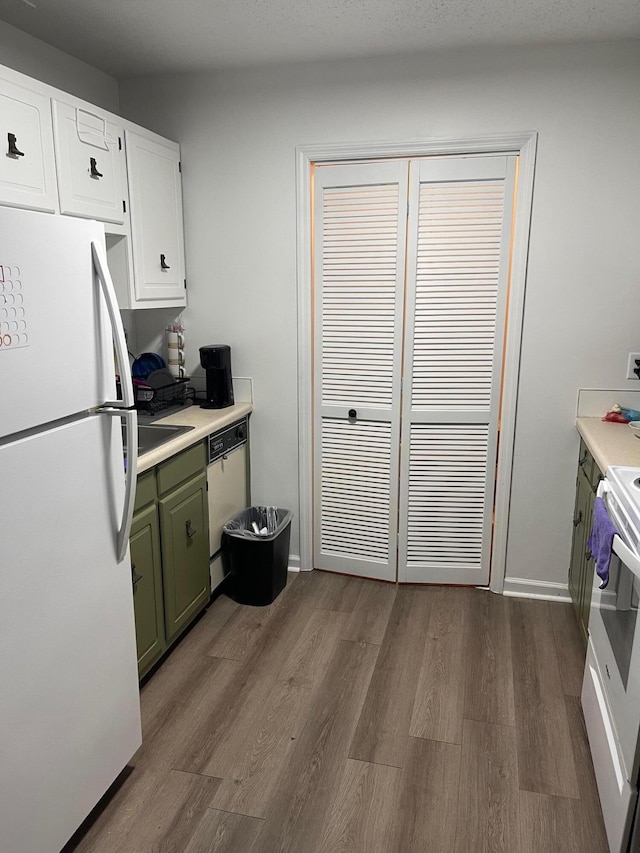 kitchen with white appliances, white cabinets, green cabinets, and dark hardwood / wood-style flooring