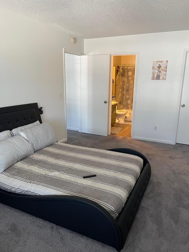 bedroom featuring a textured ceiling, carpet flooring, and ensuite bath