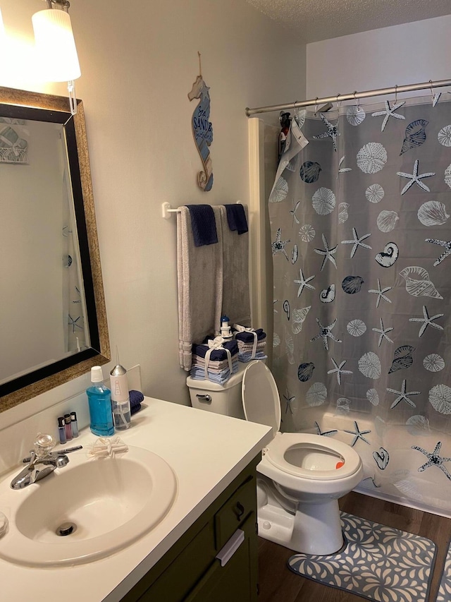 bathroom featuring toilet, wood-type flooring, curtained shower, vanity, and a textured ceiling