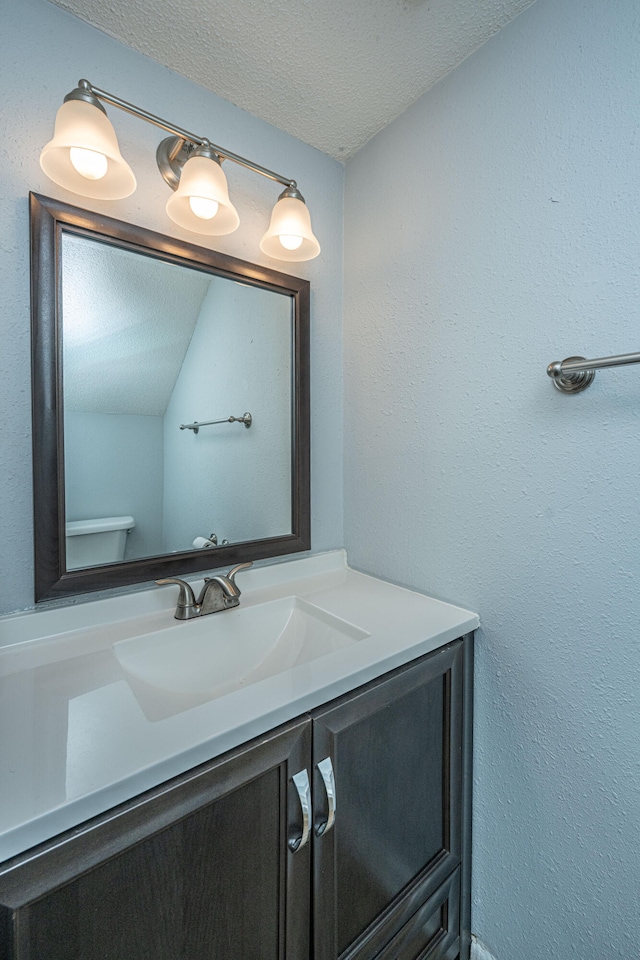 bathroom with vanity, a textured ceiling, toilet, and lofted ceiling