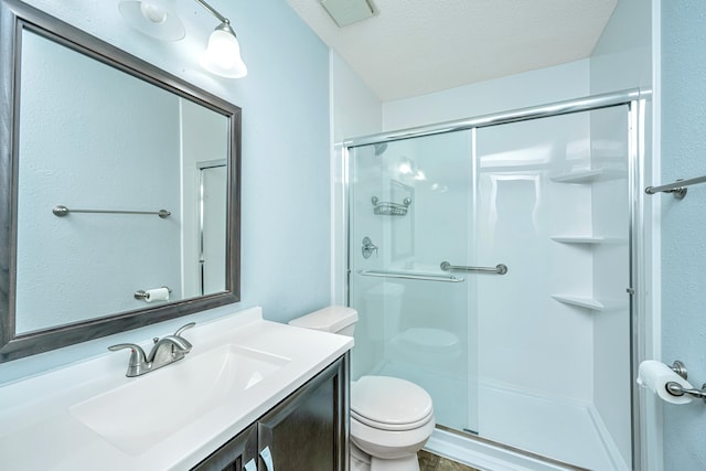 bathroom featuring vanity, a textured ceiling, toilet, and a shower with shower door